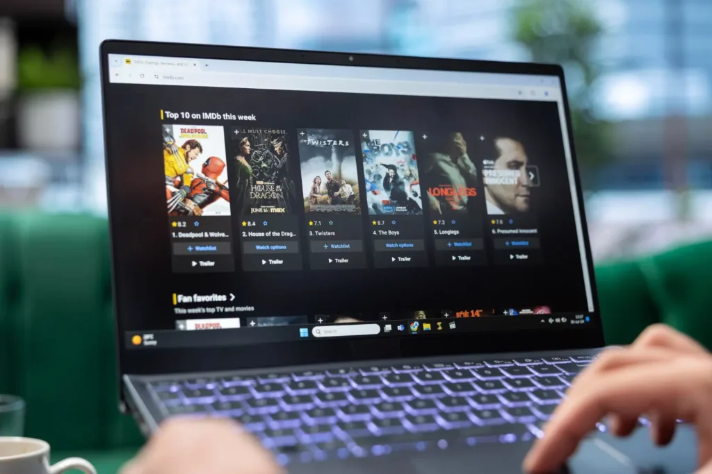 Person streamar IPTV på laptop med IMDb topplista över filmer och serier
